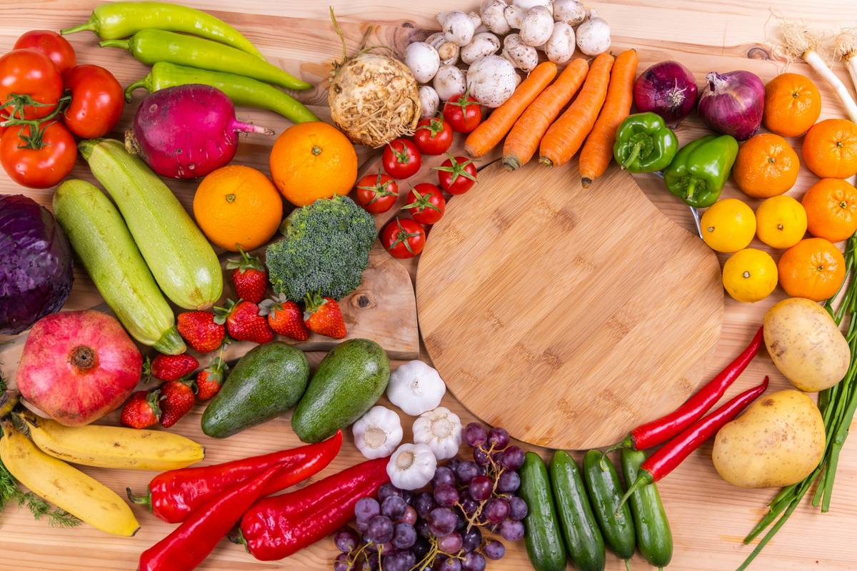 A hand holding a bag of organic soil-to-snack foods next to fresh produce on a rustic wooden table
