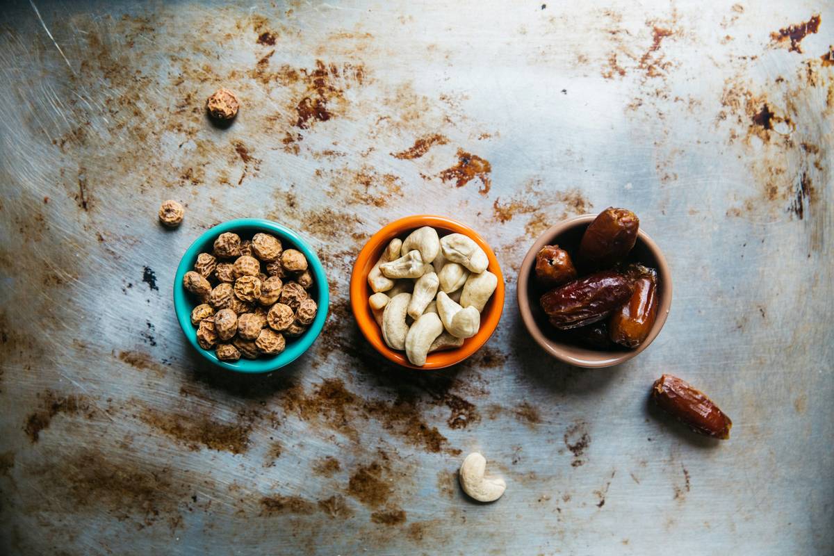 Assortment of organic non-GMO snack options including nuts, dried fruit, and seed bars on a wooden table